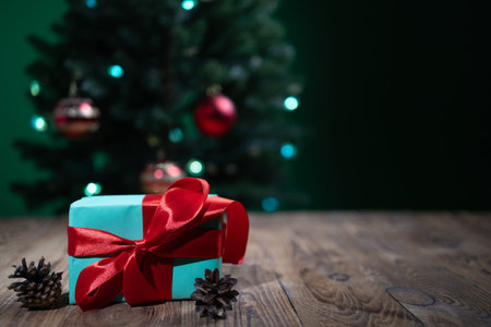 A beautifully wrapped gift sits on a wooden surface, surrounded by pinecones, while a decorated...