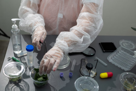 A researcher in protective gear examines aloe plant samples in a lab. Various testing materials and...