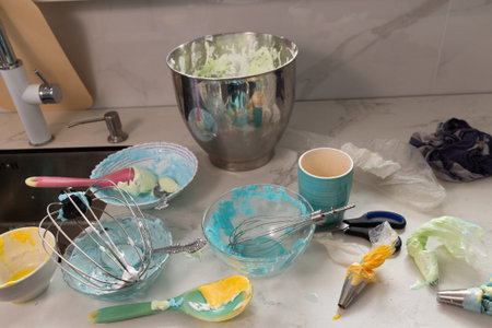 A pastry chefs workspace is filled with colorful bowls of meringue and whipped cream, along with...