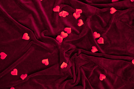 Red velvet fabric serves as the perfect backdrop for scattered heart decorations. Ideal for digital...