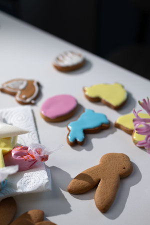 People are baking gingerbread cookies in various shapes related to Easter. Some cookies are...