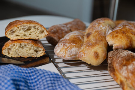 Bread is placed on a cooling rack with some loaves shown whole and one sliced on a wooden board. A...