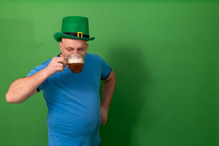 Man wearing green leprechaun hat toasting with foamy pint of beer. St. Patricks Day festive...