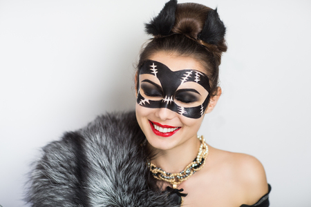 Stylish girl in a mask Catwoman decorated natural grey black fur, red lips, small kitten ears, luxury jewelry. Perfect art idea for carnival Halloween party, animation team or dancer actress stripperの写真素材