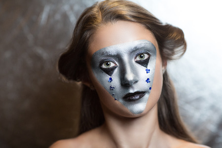 Young beautiful bright showy girl - lady model robotic queen. Fairy tale future party disco techno club. Art makeup flawless face silver eyes cheeks eyebrows black lips. Facial mask hair dressの写真素材