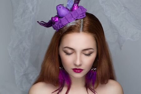Close-up portrait of perfect woman face. Bright make up - red lips, shadows long lashes. Creative hair dress with purple birds sitting on head, pigeon mail. New crazy art fashion beauty magazine ideaの写真素材