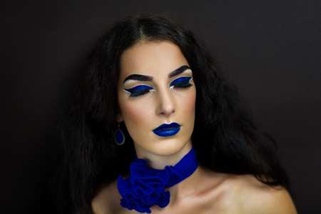 Young beautiful girl,woman, lady,witch, black bride, widow. Night background ,darkness, death. Bright fantasy makeup, big blue lips, expressive eyebrows, arrows. Chic look Halloween, beauty magazineの写真素材