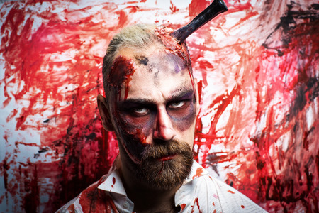 Creative man guy with a beard model blood red color wall. Bright conceptual art make-up glows light Halloween party time. Dark lifestyle, bad thoughts to eat person meat, destroy have funny weekendの写真素材