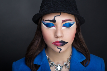 Creative make-up new conceptual idea for Halloween. Pink red black white electric blue bold body art painting. Crazy new graphic abstract picture on woman face. Dark lips Horizontal professional photoの写真素材