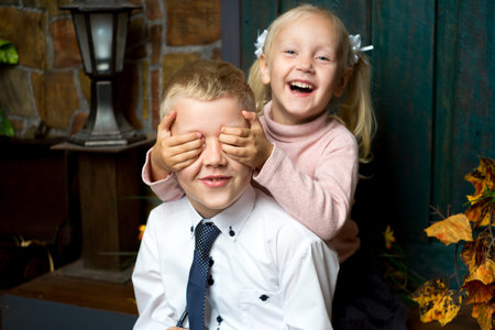 Little children hug and smile. Boy girl are playing hide and seek. Friendship affection, copying of adult behaviour social roles, small model of family. older brother younger sister laugh surprise joyの写真素材