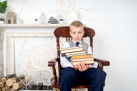 handsome boy holding in his hands stack of books, educational literature. conceptual idea about modern education system. a guy dreams of his future profession, good diligent student in school, collegeの写真素材