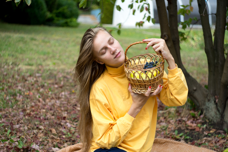 Beautiful woman relax in the garden, sits on a wool blanket. beauty of nature, autumn park. Round shape wicker basket, daylight illuminates plants. picnic in the village, fresh air. horizontal bannerの写真素材