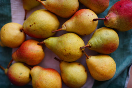 big colorful pears on a green napkin kitchen towel, tasty fruits decorates summer garden. beauty...