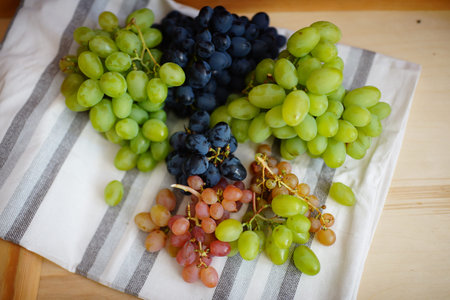 big blue violet green grapes on a napkin kitchen towel, curly grape bunch decorates summer garden....