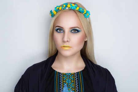 Beautiful very bright blond woman in traditional Ukrainian embroidery. National colors yellow and blue fancywork cross stitch. Young Cossack brave warrior patriot of country and glorious city of Kievの写真素材