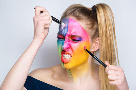 Girl painter holds black artist professional brush, all body Painted in gouache watercolor acrylic oil paints. Creative makeup new conceptual idea. Crazy new graphic abstract picture woman face linesの写真素材