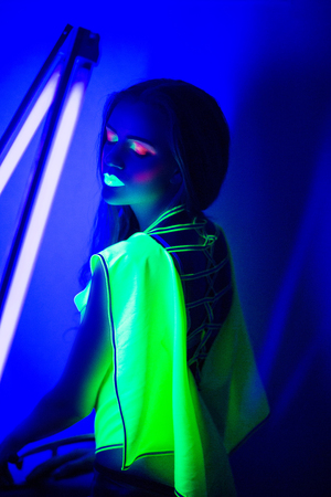 Creative woman lady girl model shine with blue green orange colors. Bright conceptual art make-up glows under ultraviolet light. Club disco neon party time. Drink alcohol feel wild energy of musicの写真素材