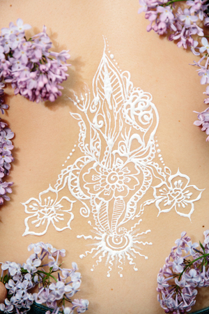 Drawing mehendi on white skin woman back. White picture abstract flowers sun flame.の写真素材
