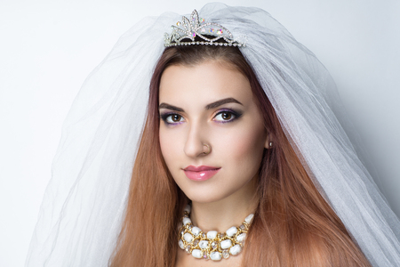Beautiful bride woman girl lady princess prepare for wedding white long veil, silver diamond crown, necklace accessory. Professional make up bright eyes, pink lipstick. background free placeの写真素材