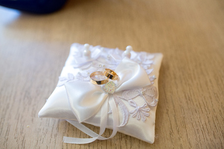 Big white pillow and Two Wedding Rings. Goods for wedding. photo is perfect for magazines, shops dealing with wedding dresses ceremonies bride groom marriage jewelry. Can be used for poster or websiteの写真素材