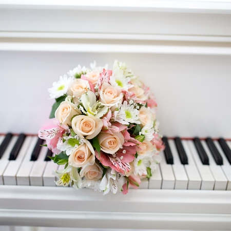 Big white black Piano keys and Two Wedding Rings. Flower bouquet composition of cream red yellow roses. Pleasant melody of unfading love, pure sublime feelings of two loving hearts. Concept conceptualの写真素材