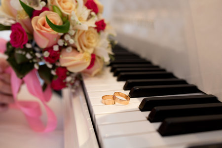 Big white black Piano keys and Two Wedding Rings. Flower bouquet composition of cream red yellow roses. Pleasant melody of unfading love, pure sublime feelings of two loving hearts. Concept conceptualの写真素材
