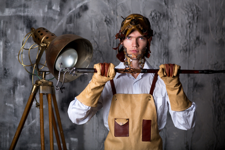 Man steam punk style, art make-up. Guy face decorated with gears from clock, new idea. colorful bold face-art painting graphic abstract picture. Conceptual post-apocalypse word. Traveler or scientistの写真素材