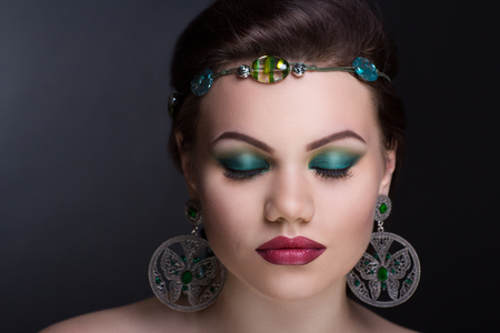 Close up portrait woman make up. Big silver round circle earrings, green tiara accessory decorates hair, artificial transparent stones. Horizontal banner, new conceptual idea. Professional photo modelの写真素材