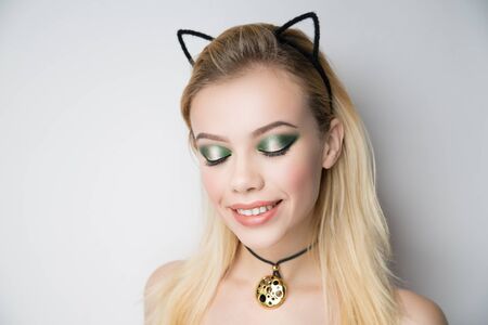 Young beautiful bright showy girl lady model kitten queen. Fairy tale future party cosplay club. new makeup flawless face, green eyes, beige cheeks eyebrows lips. cat ears, blonde volume straight hairの写真素材
