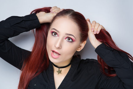 Beautiful woman emotional face. Combed straight bright red cherry hair. Professional cosmetics makeup. Shiny matte lips lipstick lip-gloss. New photo close up portrait, gray color background bannerの写真素材