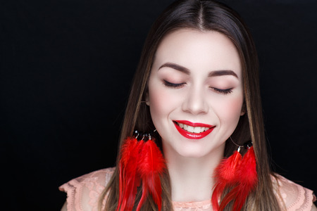 Closeup portrait of beautiful girl woman lady with volume combed hair styling. Luxury red earrings jewelry. Bright shadows makeup, shiny matte lips lipstick lip gloss. Professional photo model personの写真素材