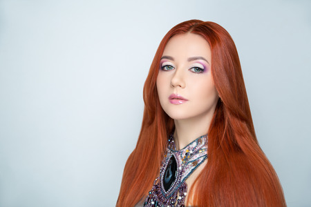 Close-up portrait of beautiful girl pretty lady with professional makeup, violet arrows, red hair styling. Luxury New Bright color make-up shiny lips lipstick glossy cosmetics. photo conceptual ideaの写真素材