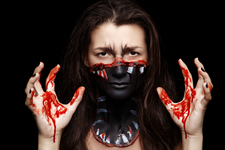 New creative make-up, conceptual idea for horror Halloween night party. Black color mouth, white sharp teeth, bloody lips, cosmetics shadows paints. Professional close-up photo. crazy skin paintingの写真素材