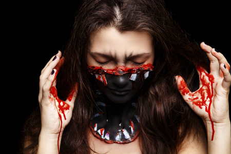 New creative make-up, conceptual idea for horror Halloween night party. Black color mouth, white sharp teeth, bloody lips, cosmetics shadows paints. Professional close-up photo. crazy skin paintingの写真素材