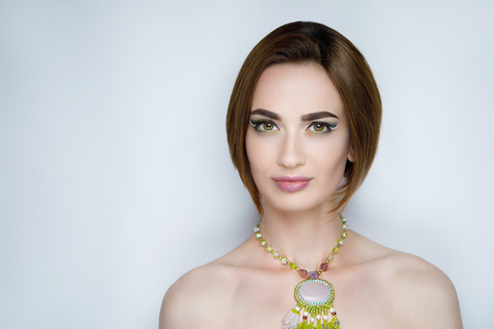 New creative make-up, conceptual idea. Green shadows, vivid colors graphic shapes lines, art cosmetics paints, colorful necklace jewellery. close-up photo. skin painting artistic. perfect pastel mintの写真素材