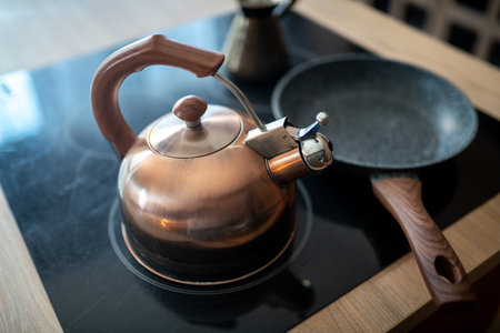 Old classic aluminum kettle on a black glass plate. Necessary object in the kitchen. Big non stick...