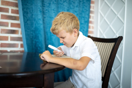 Young handsome boy, white hair, an official short-sleeved shirt. He is sitting at the table holding...