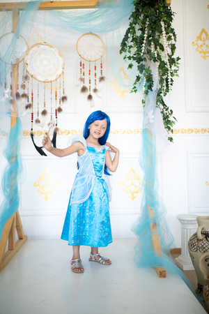 Beautiful little girl in a blue wig. Long hair with bangs. Beautiful evening dress for a costume party for Halloween. Pretty fairy conjures and fantasizes, a magic sorceress. Fun Entertainment enjoyの写真素材