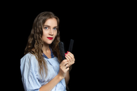 Beautiful girl with very confident face holding black comb, hairbrushes. On her eyes arrows, nude...