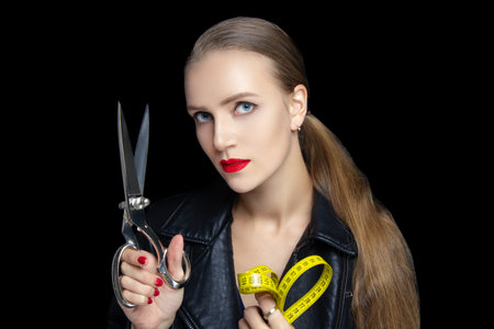 Young beautiful girl with very confident face holds big sewing scissors. Sharp silver blades for...