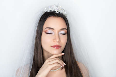 Beautiful woman skincare concept. Bright makeup shades shadows sequins. Perfect hairstyle brushed long straight hair. background horizontal banner. Big massive accessory. Gentle hand touches her cheekの写真素材