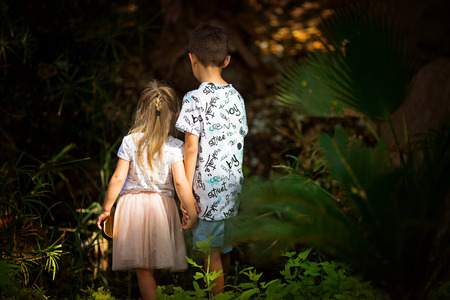 Happy laughing kids play in beautiful sunny park little boy and girl watching toadstool mushroomの写真素材