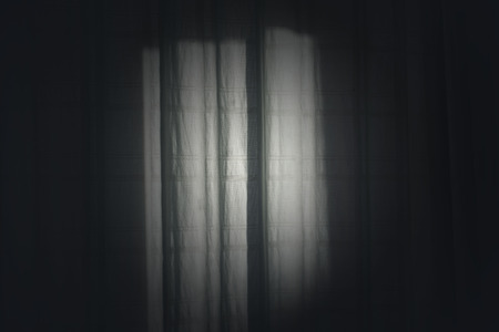 Silhouette of curtain in illuminated windowの写真素材
