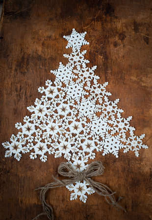 Christmas Card with White Snowflakes in the Form of a Fir tree on a Wooden Surfaceの写真素材