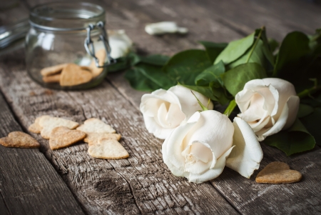 Three White Roses and Pastry on the Wooden Table Backgroundの写真素材