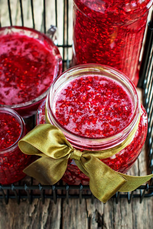 Fresh Raspberry Jam in open jars on the wooden table, close up