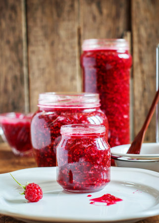 Jam from Raspberrys in an open Jars on the wooden backgroundの写真素材