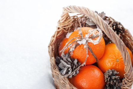 Christmas Oranges with Sticky Snow on Bow from Cord a and Pine Cones in Watlled Basket at the Snow, horizontalの写真素材