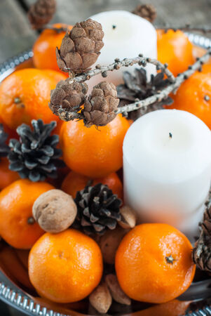 Holiday Composition with Tangerines, Pine cones, Walnuts, Candles and Almonds on Wooden Table, holiday decorationの写真素材