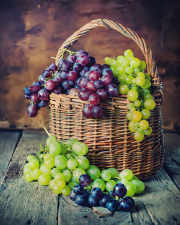 Rural Basket with Green and Red Grapes on Wooden Background. Country styleの写真素材